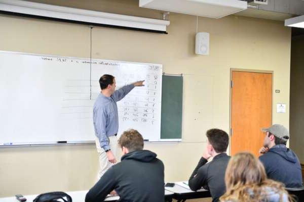 High school students listen to the instructor during Economics class in BCYC Immersion